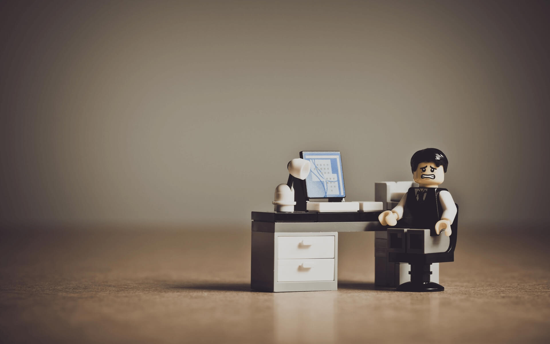 Worried lego business man sits at a lego desk